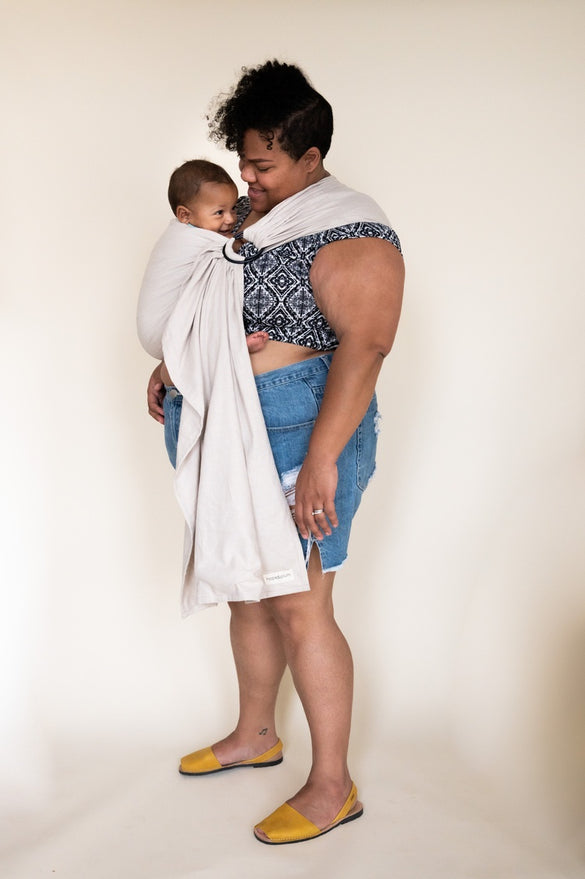 Black mother holding her baby in an extra-long ring sling. 