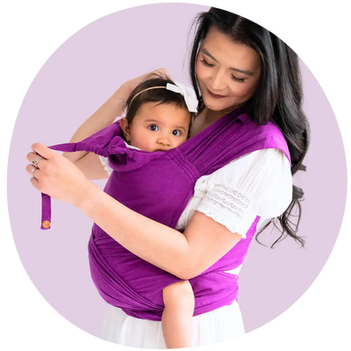 An Asian mother smiling and babywearing her toddler in a purple meh dai carrier