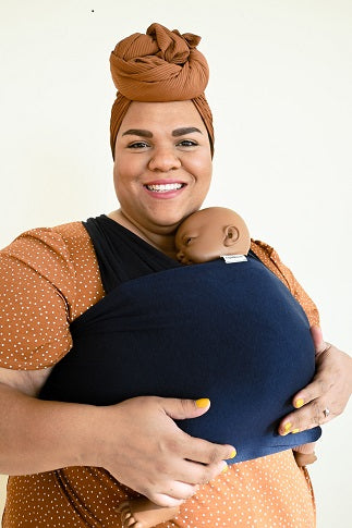 Plus Size Black mother wearing infant in dark blue baby wrap carrier. 