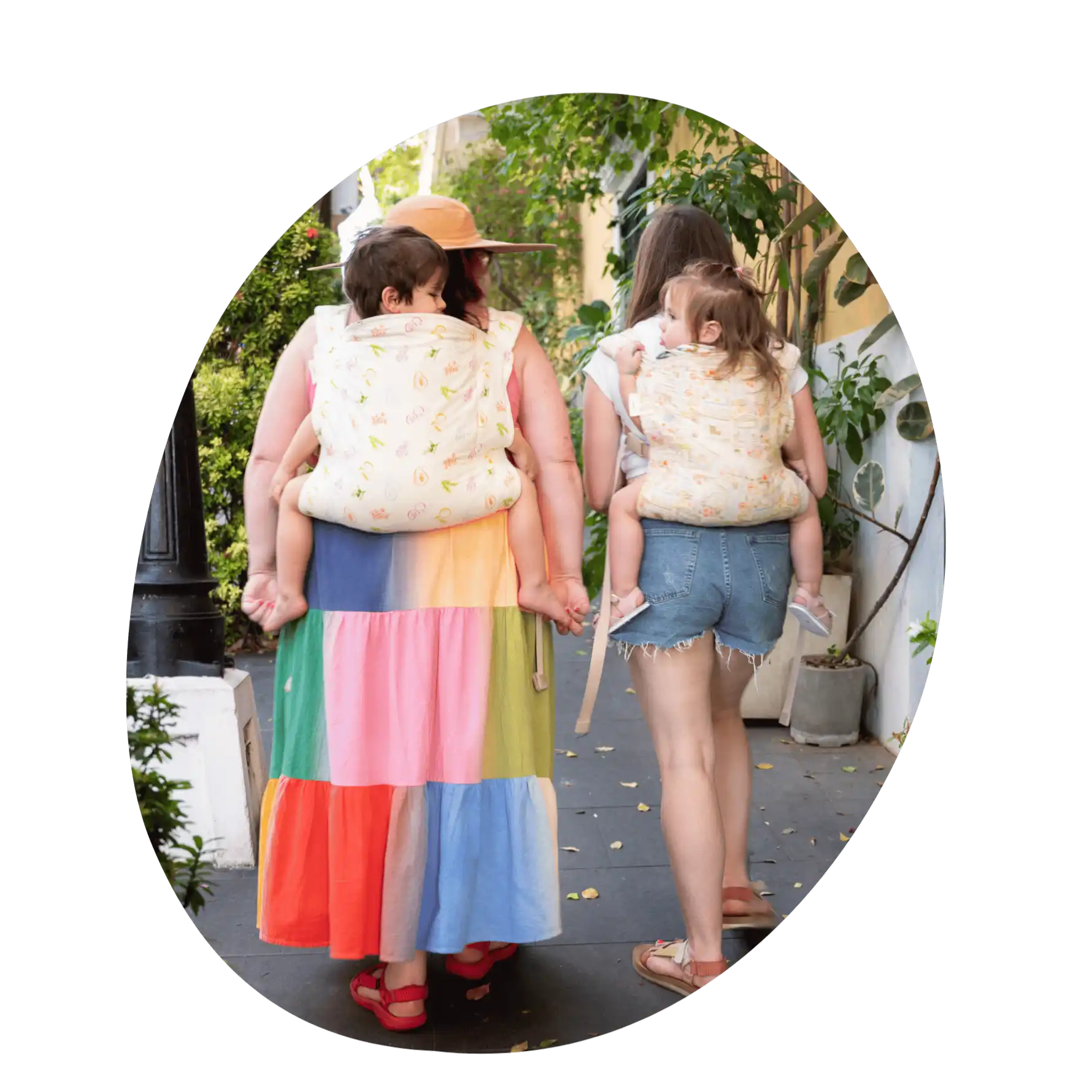 Two women carrying children in baby carriers.
