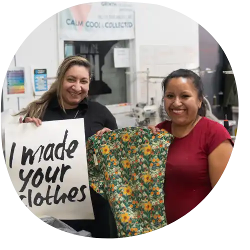 Two women holding a floral shirt and a sign.