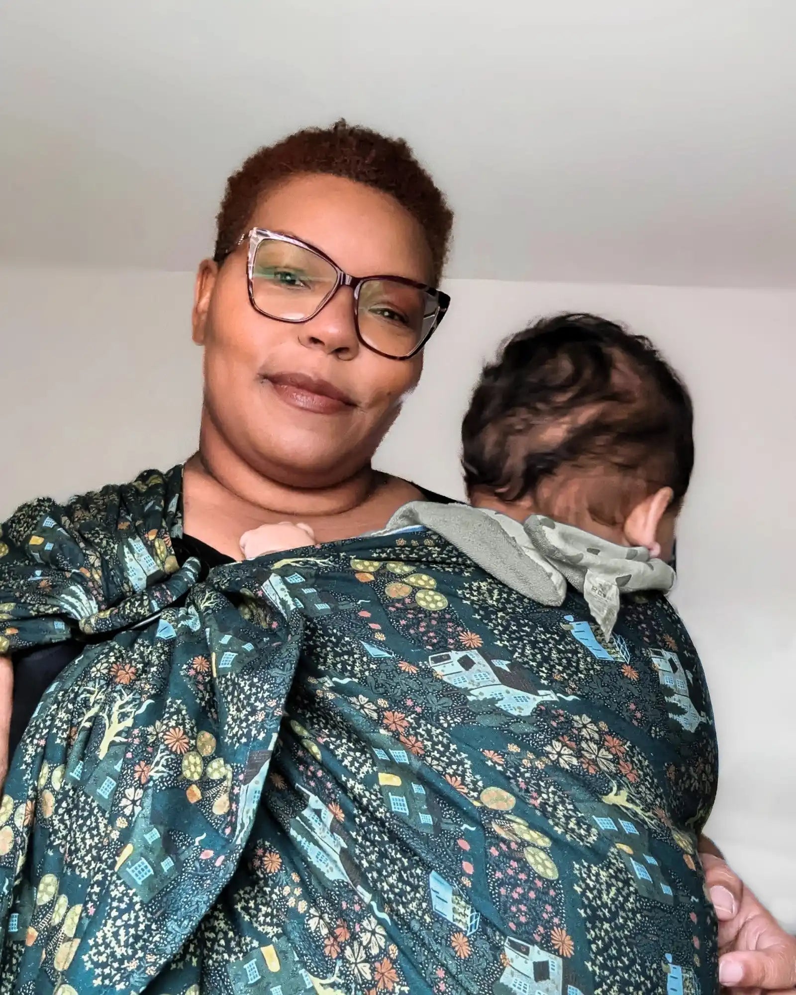 Woman holding baby in patterned sling.
