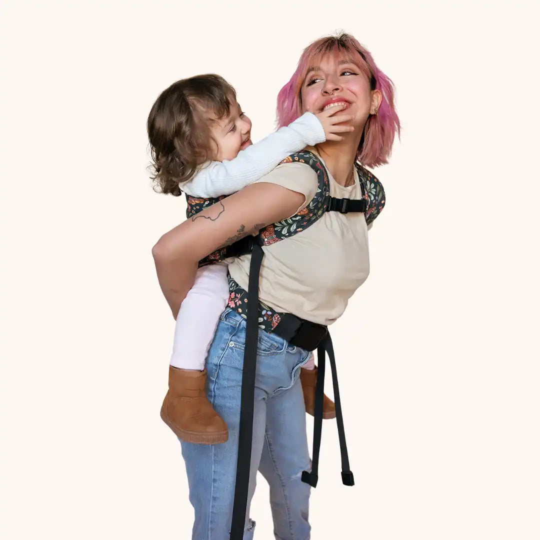 Woman carrying child in floral baby carrier.