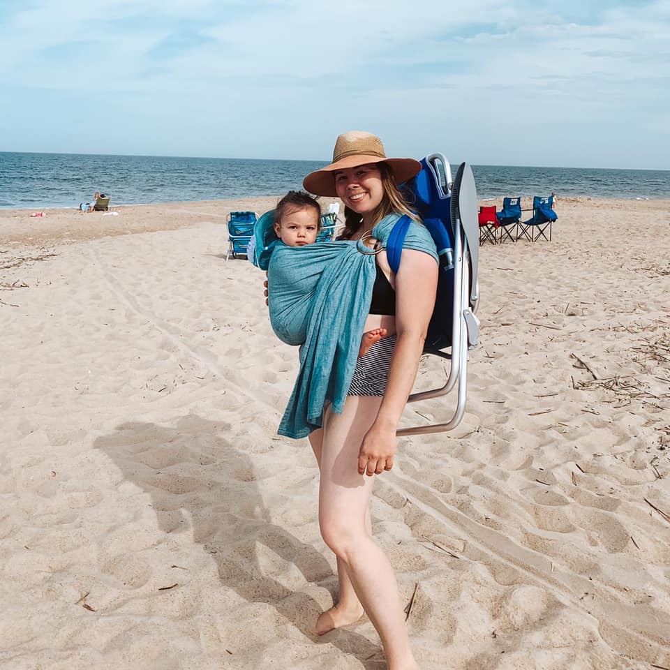 Woman babywearing her baby at the beach in the summer heat