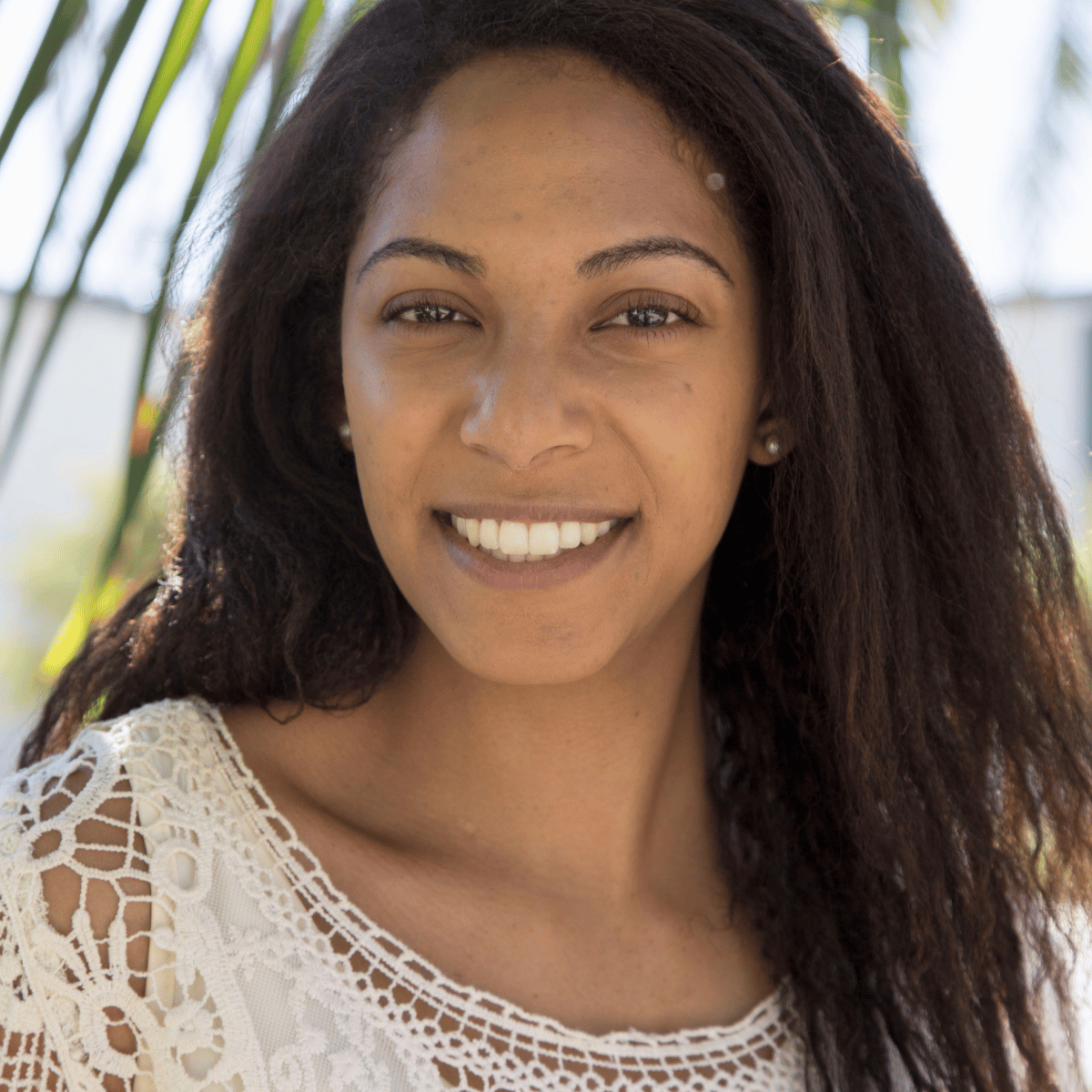A headshot of a smiling woman with brown skin and brown hair.