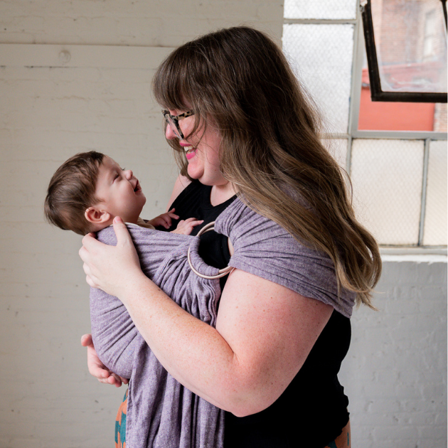 a woman babywearing her infant in a hope&plum huckleberry ring sling