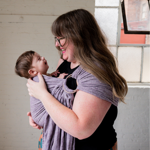 a woman babywearing her infant in a hope&plum huckleberry ring sling