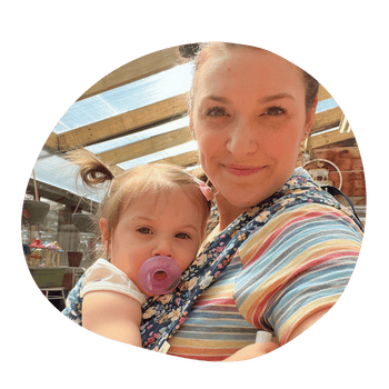 A selfie of a white straight size woman wearing her daughter on her front in an Alice Lark