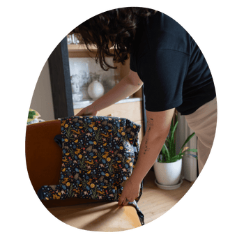 A light-skinned with  shoulder-length, dark brown curly hair  woman adjusts a Lark that is draped over the back of a chair.