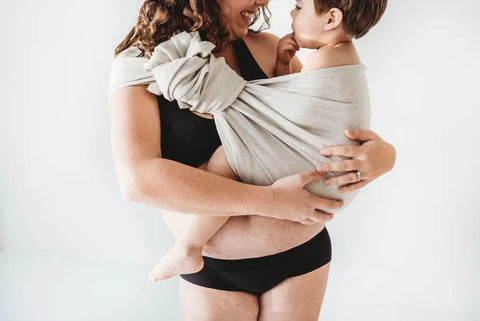 Mother holding child in a ring sling.