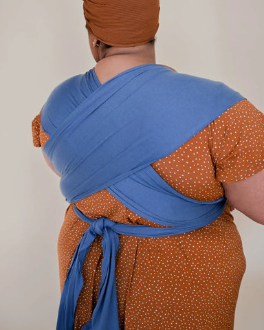 Photo from behind of mother holding baby in soft baby wrap