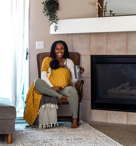 Mother wearing a baby in a golden yellow ring sling 