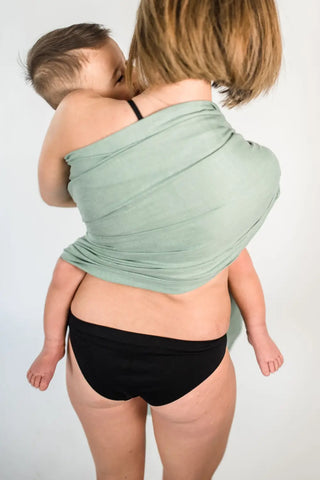 Mother facing back holding a toddler in a ring sling.