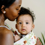 Black mother wearing infant in baby sling