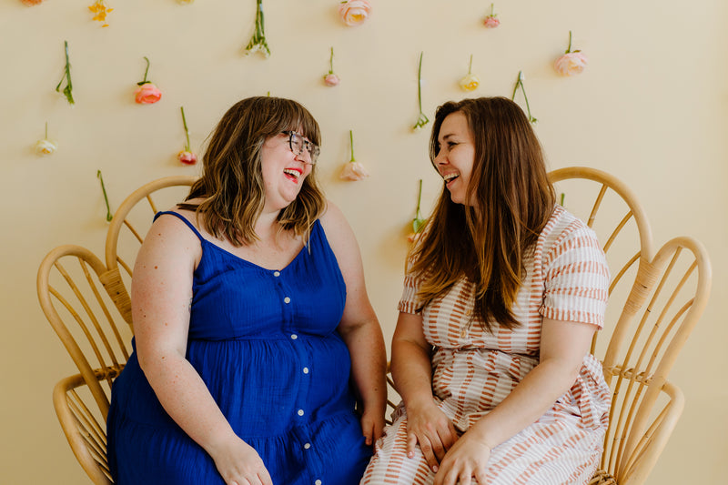 Skye and Mallory sitting together in front of flower wall. The famous hemp blend hope&plum rings sling are perfect from newborn through to the toddler years