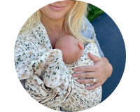 Mother holding newborn in floral print ring sling baby carrier. 