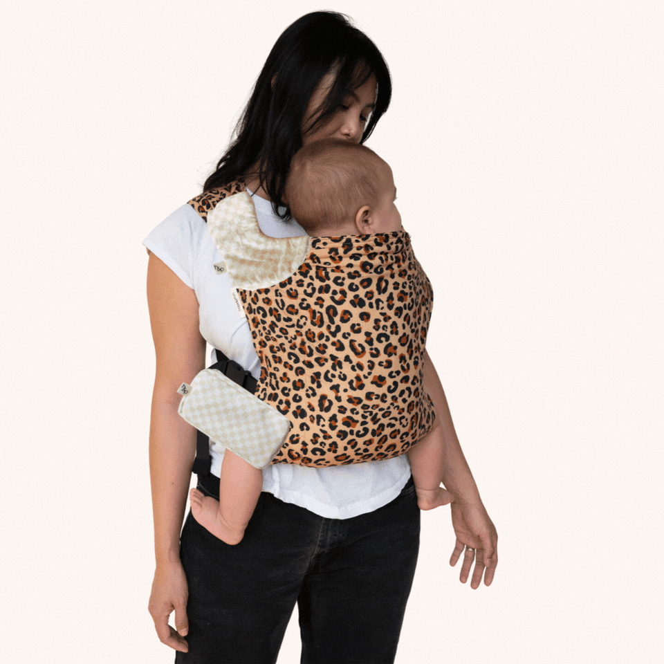 Animated GIF of the Feral Lark — a tan woven fabric with bold leopard print — as the drool pads and pocket alternate between Daisy (dark floral) and Flax (natural cream), showing mix-and-match accessory options.