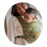 Woman holding baby in strawberry printed newborn carrier