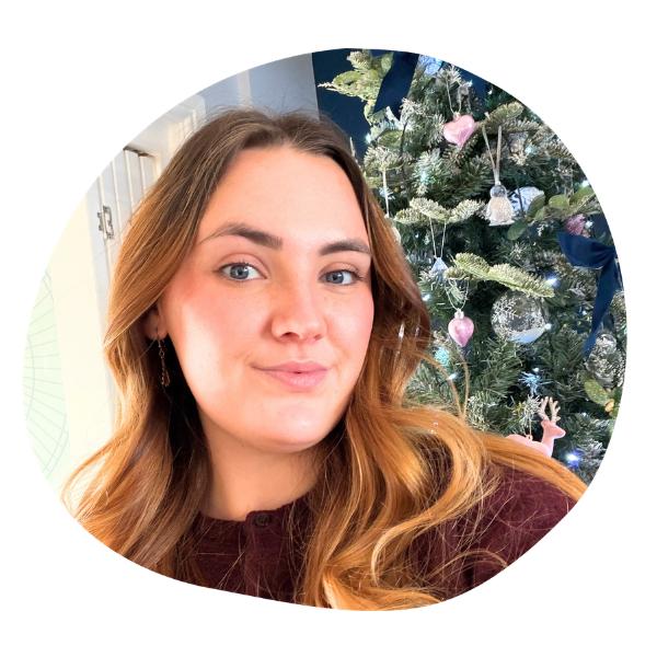 Woman with blue eyes and brown hair smiling in front of a christmas tree