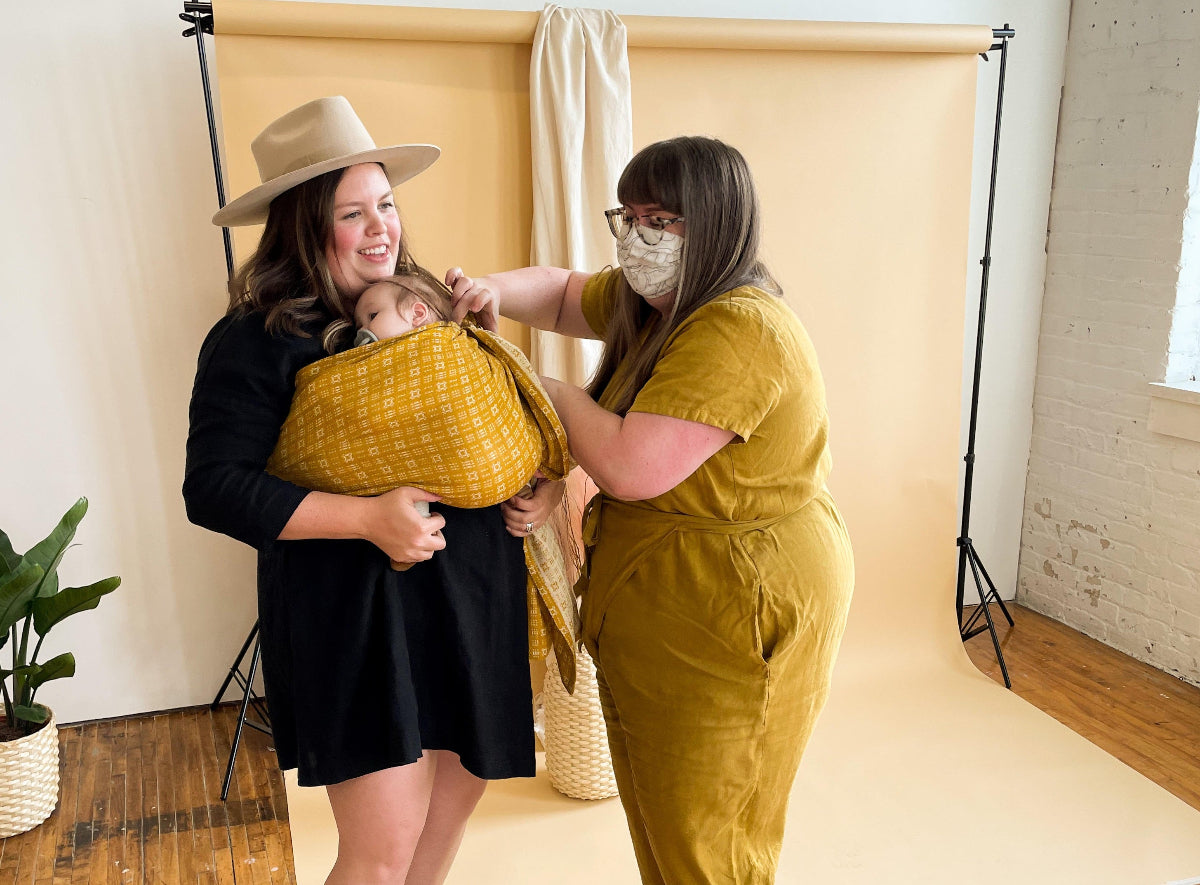 Woman helping other woman with ring sling fit. The famous hemp blend hope&plum rings sling are perfect from newborn through to the toddler years