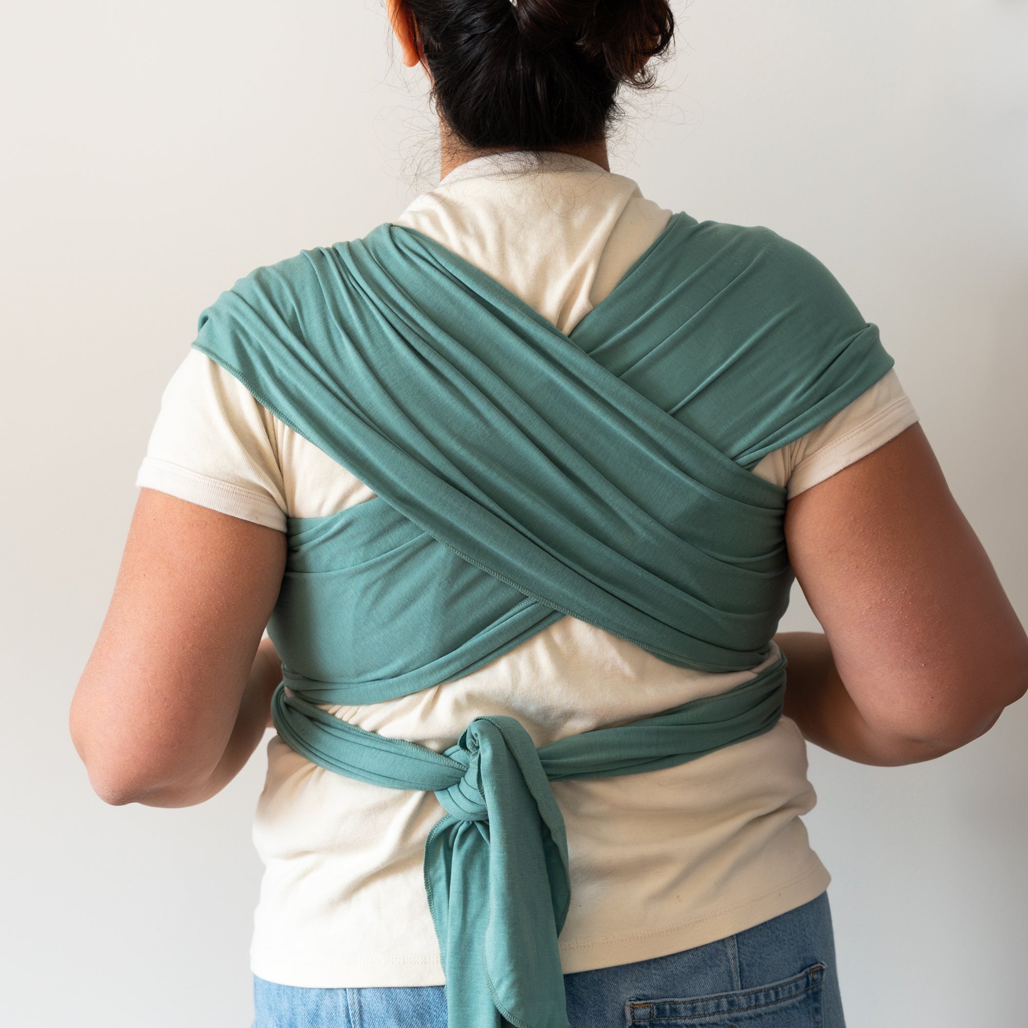 Person wearing a green baby wrap with a white background