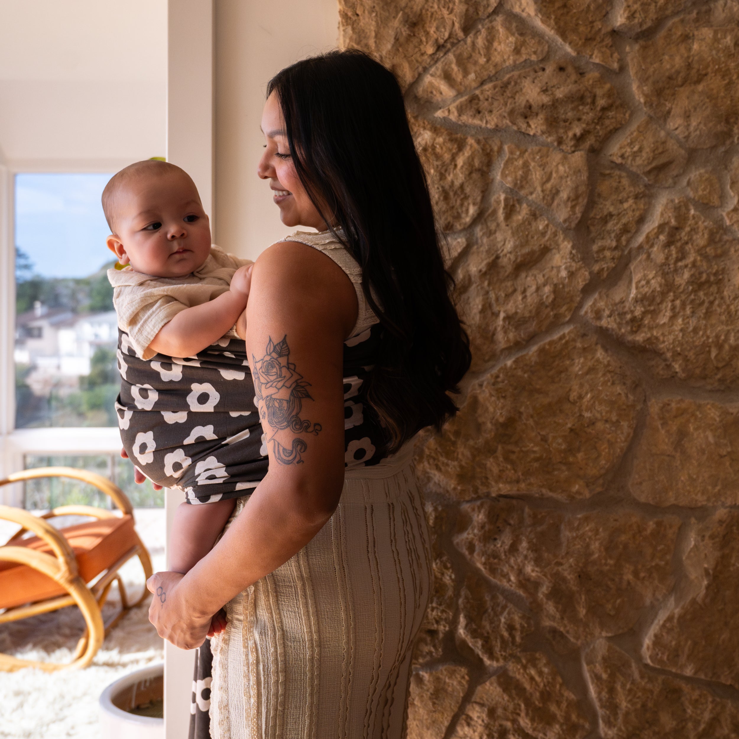 Woman holding a baby against a stone wall with a scenic view in the background