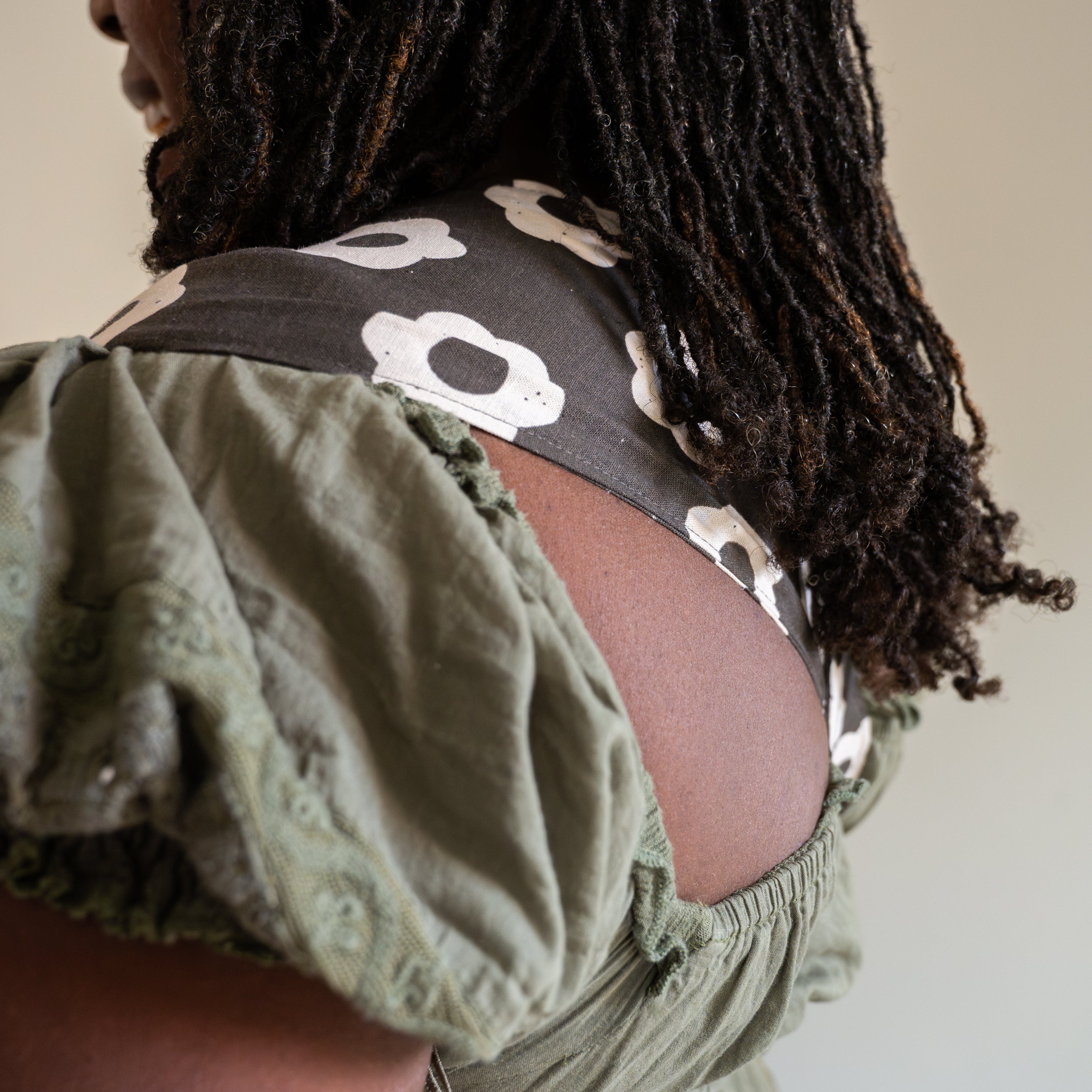 Person wearing a black and white floral-patterned newborn buckle baby carrier.
