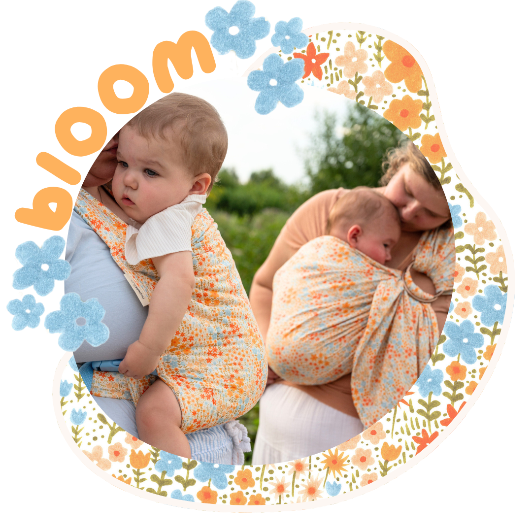 Two caregivers wear the Bloom print — a cream woven fabric with scattered orange, blue, and yellow wildflowers — one in a Lark carrying a curious baby, one in a ring sling cradling a sleeping newborn outdoors.