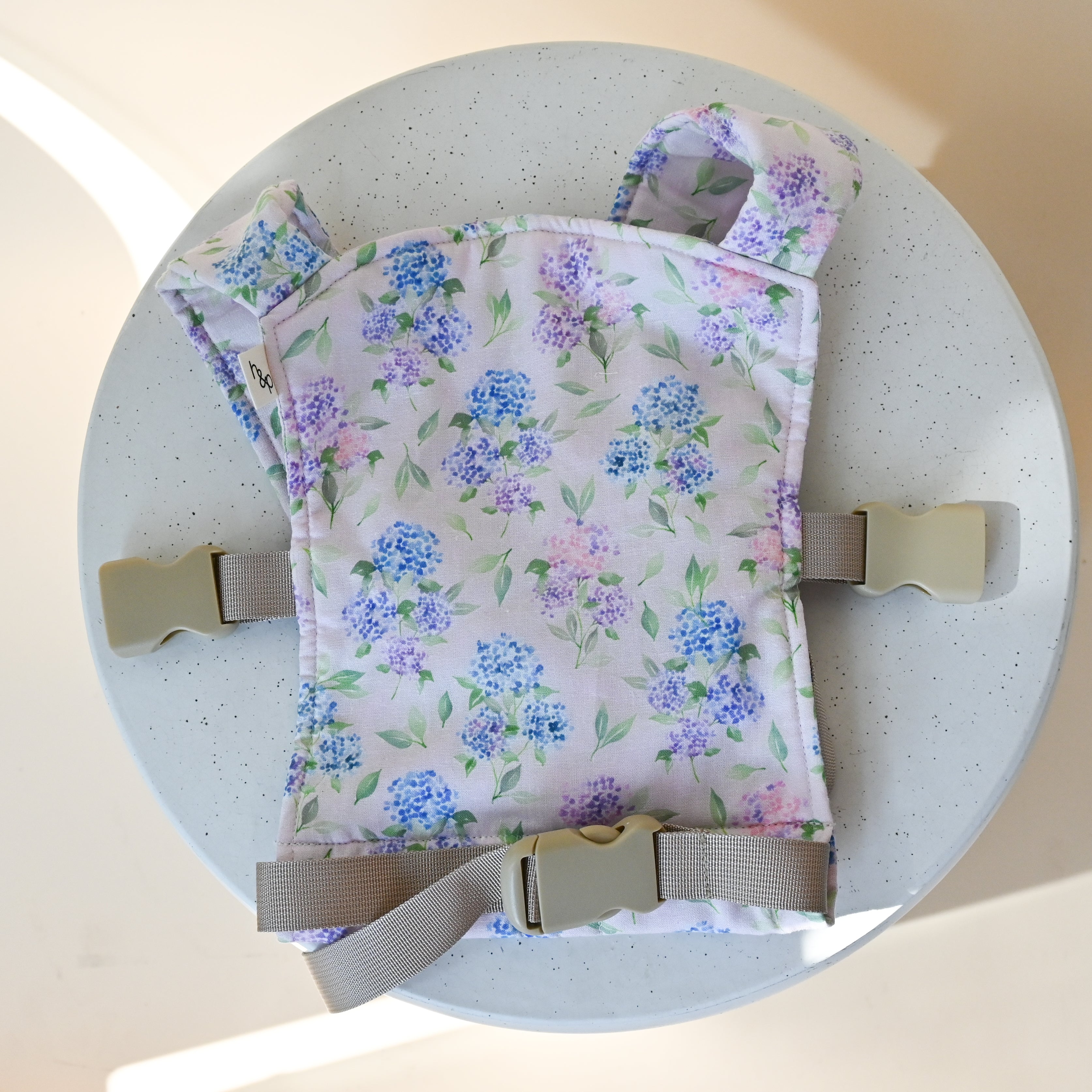 Mini Lark Doll Carrier in Blush — the miniature buckle carrier for dolls laid flat, blue and lavender hydrangea print on a soft pink background.
