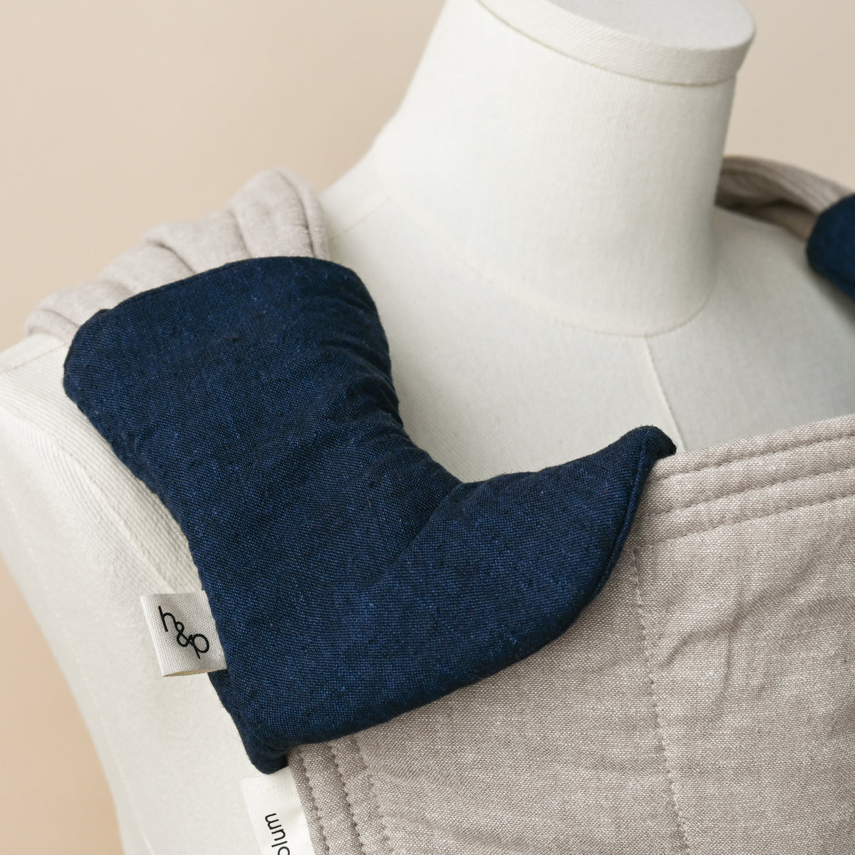 Drool Pads in Caspian, wrapped over a carrier shoulder strap on a dress form, deep indigo woven chambray with the look of dark denim.