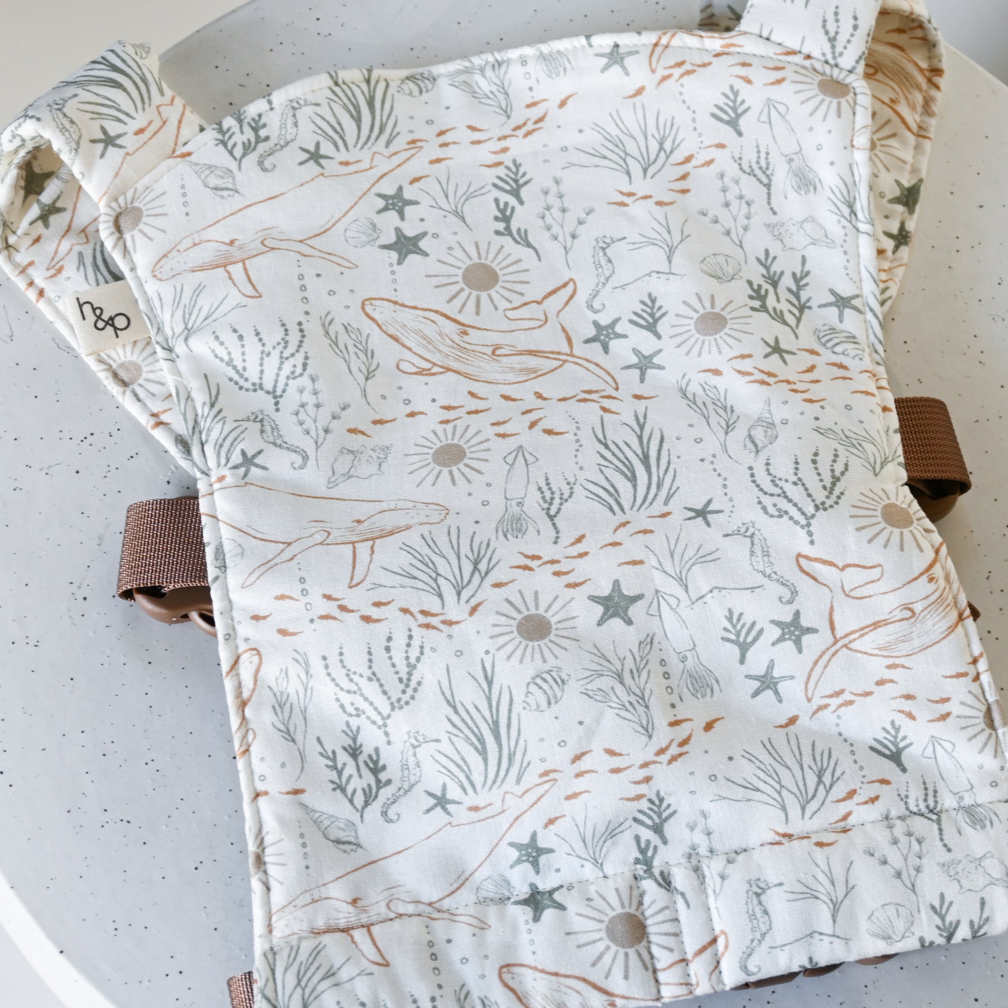 Baby doll carrier with ocean-themed pattern on a light background