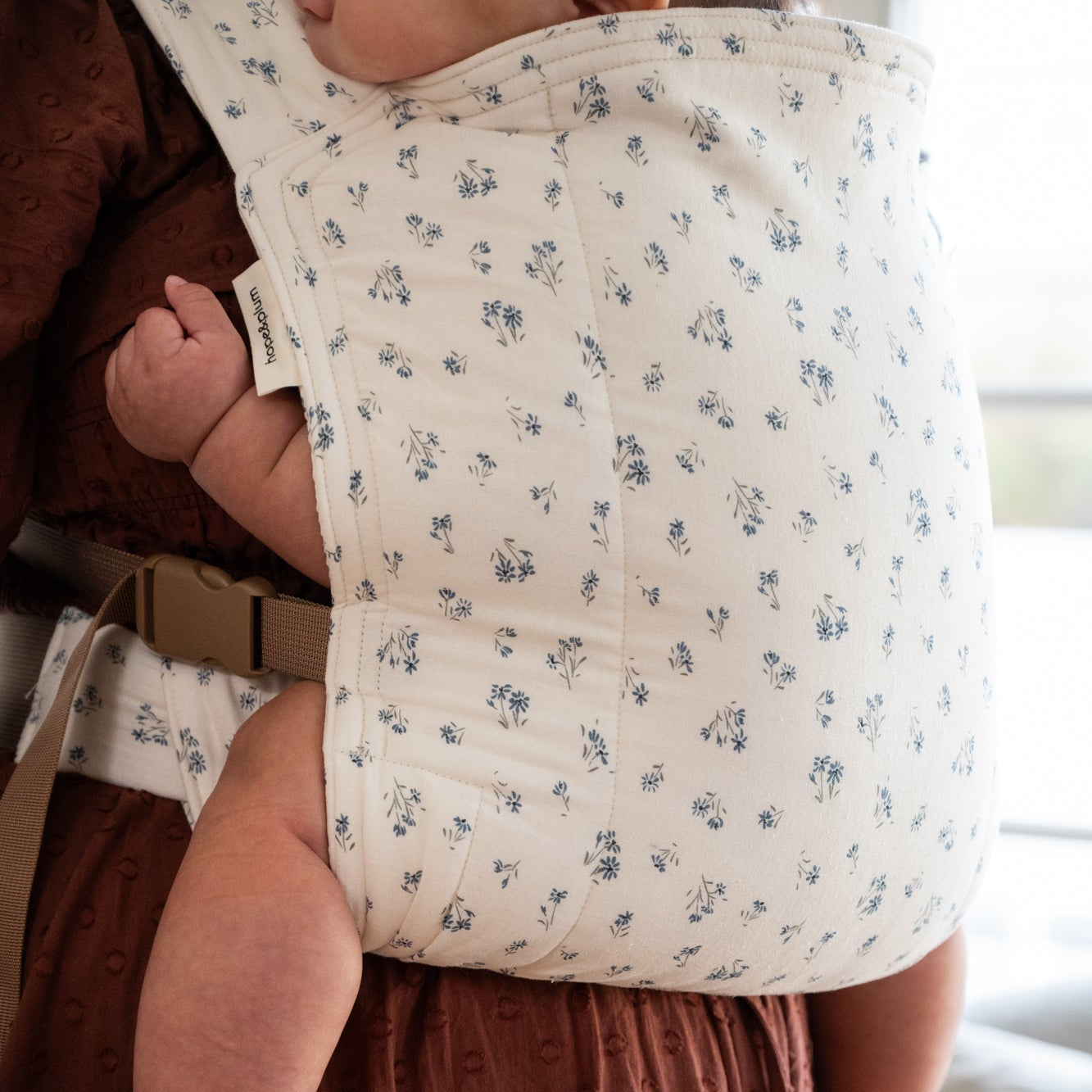 Person wearing a floral baby carrier with a child inside.
