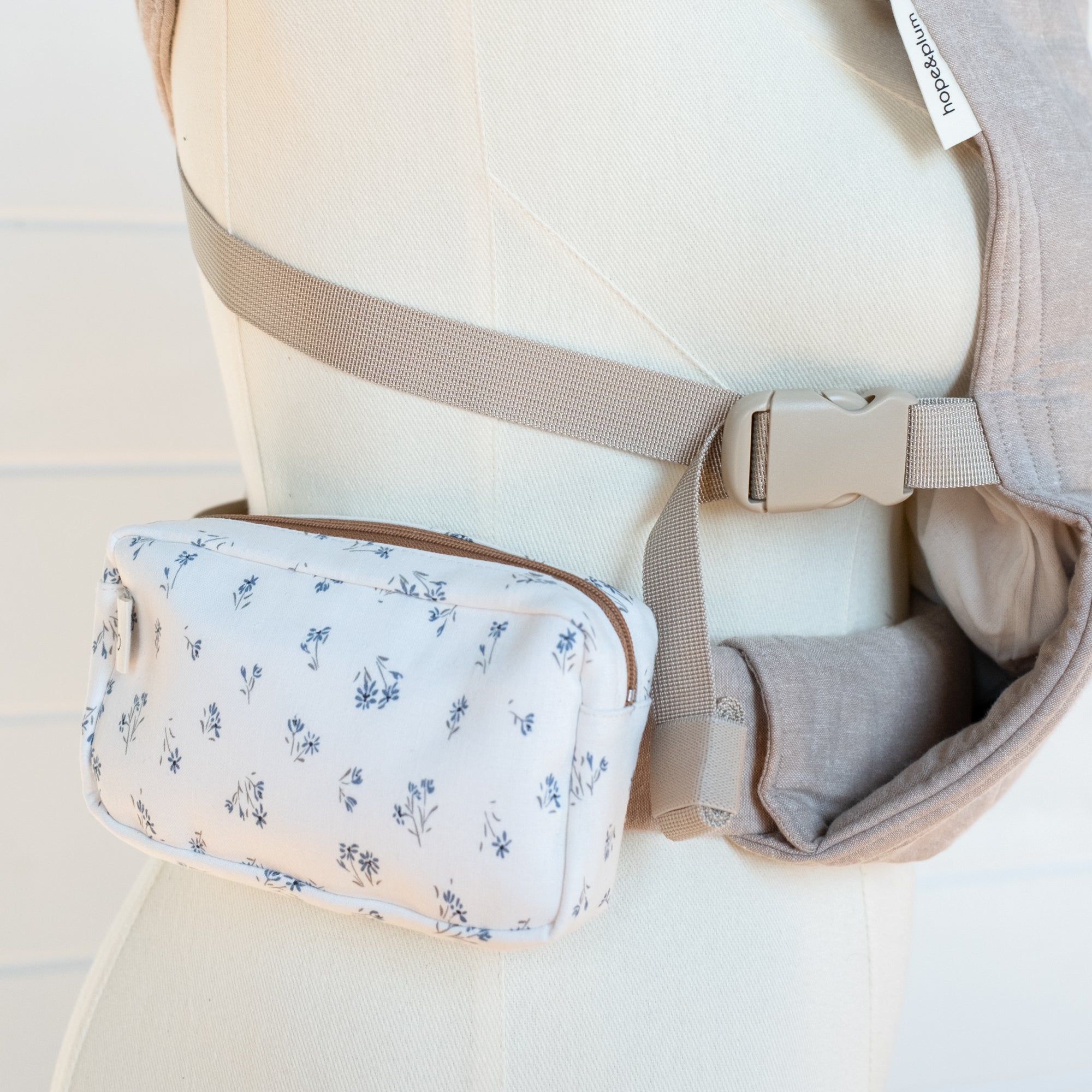 Baby carrier with a floral pouch on a light background