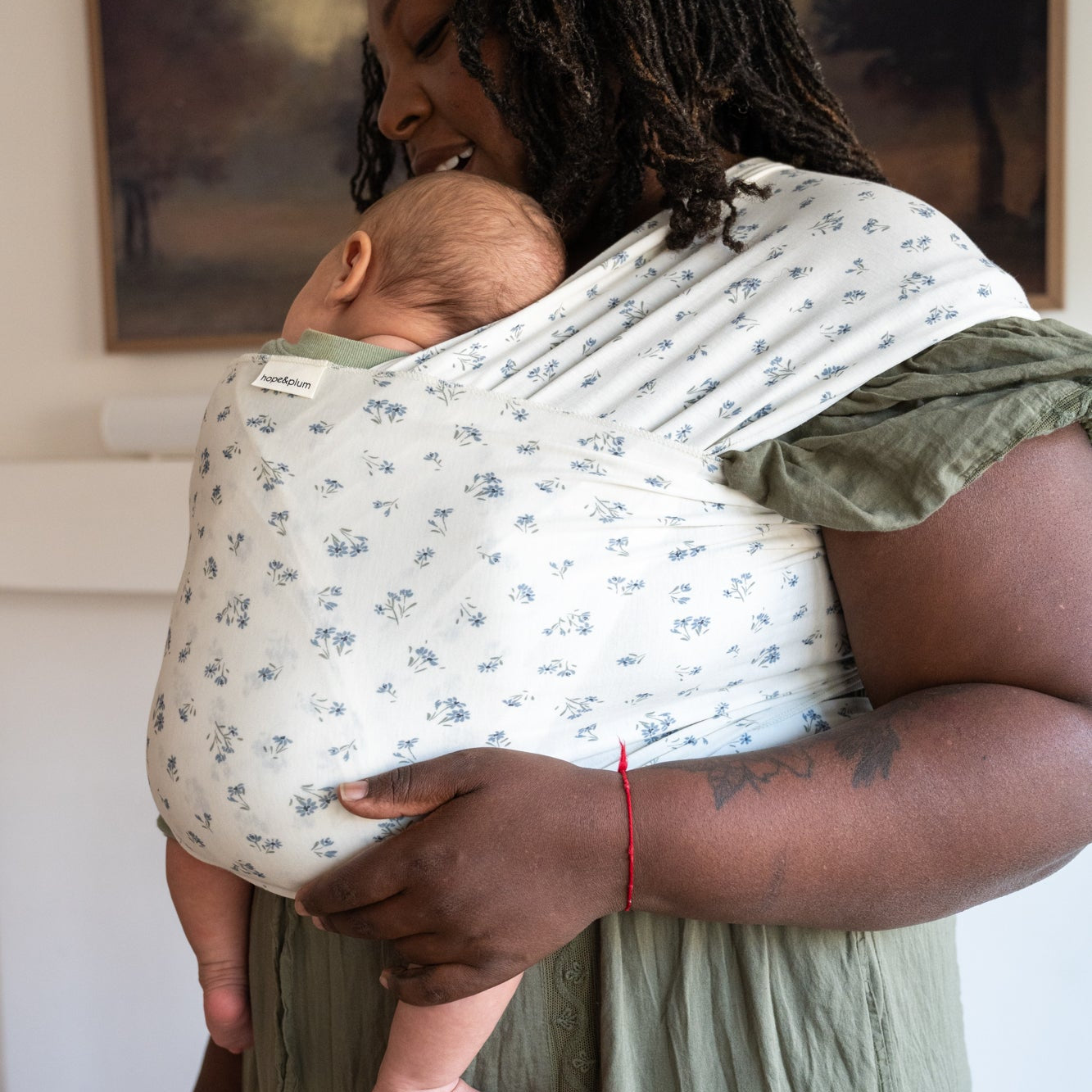 Woman holding a baby in a dainty floral wrap indoors