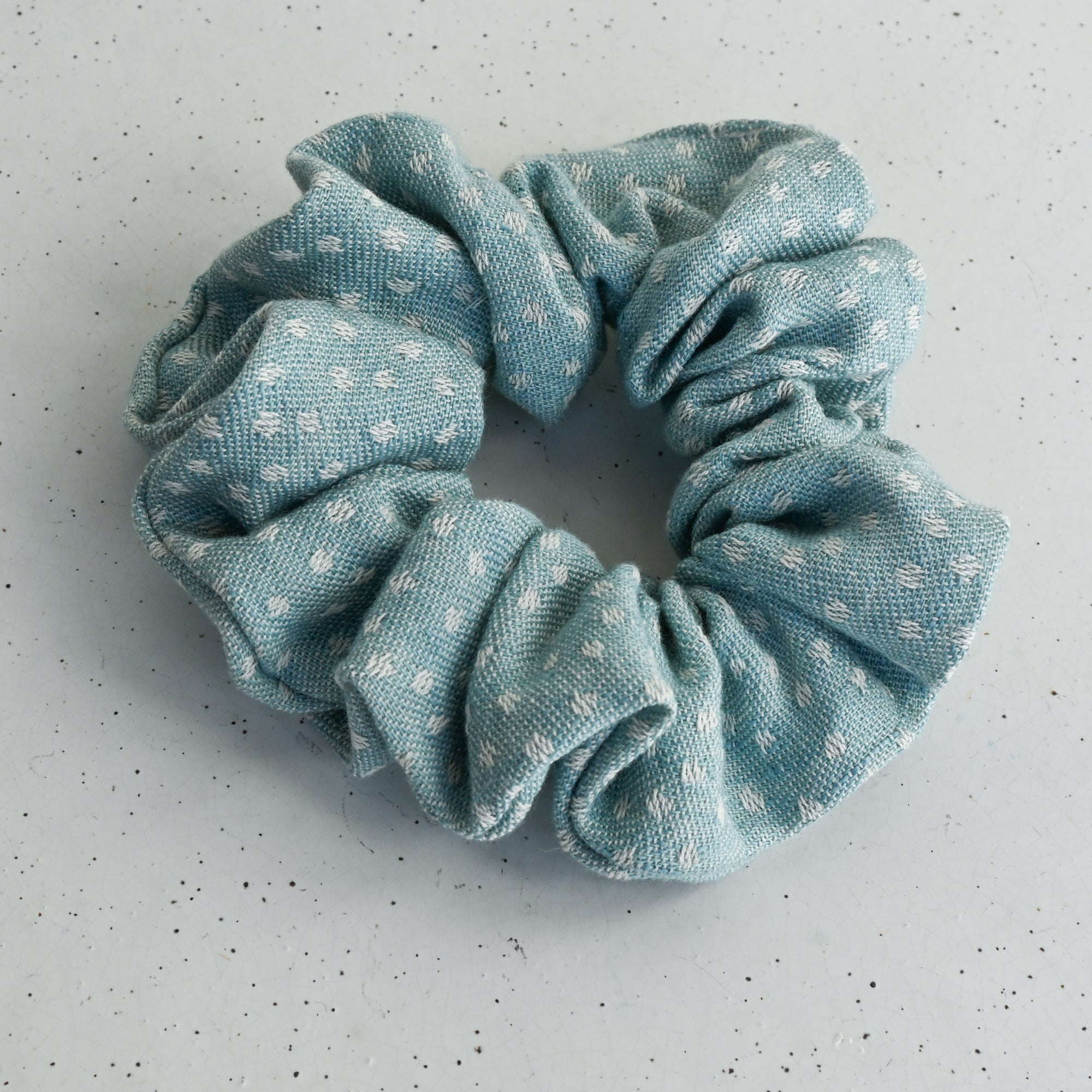 Light blue scrunchie with white dots on a white background