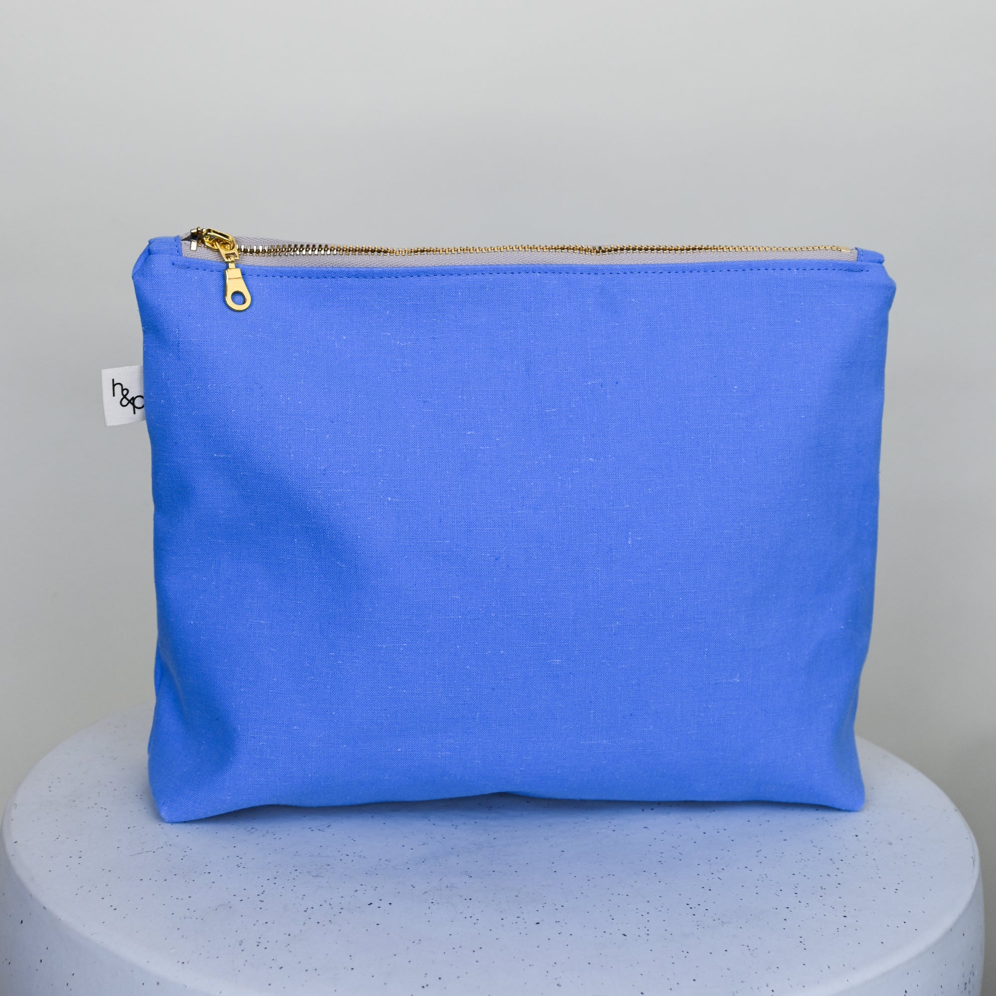 Blue pouch with gold zipper on a gray background