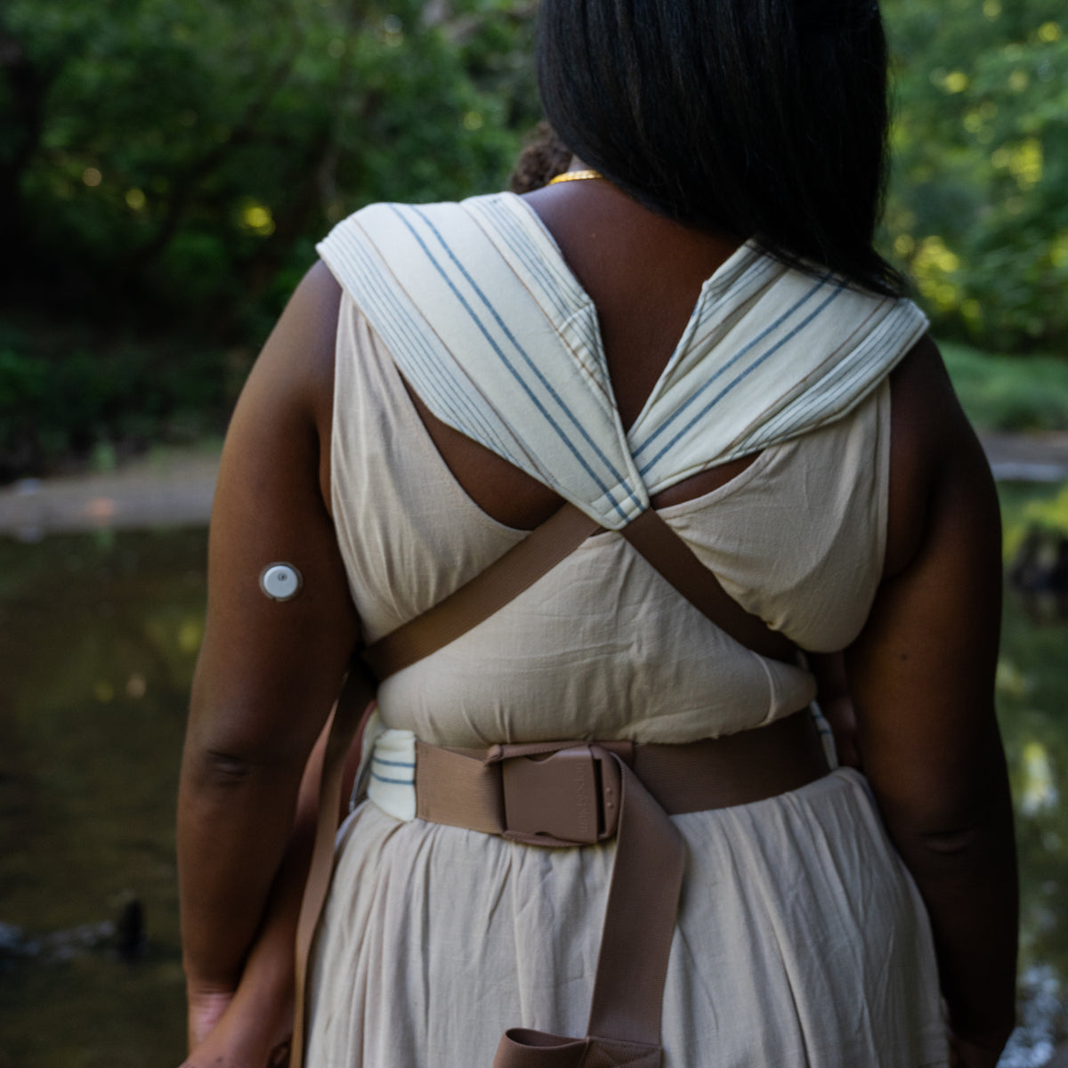 Back view of the Lugano Lark Kid Carrier showing the striped shoulder panels crossed over the back above a padded buckled waistband.
