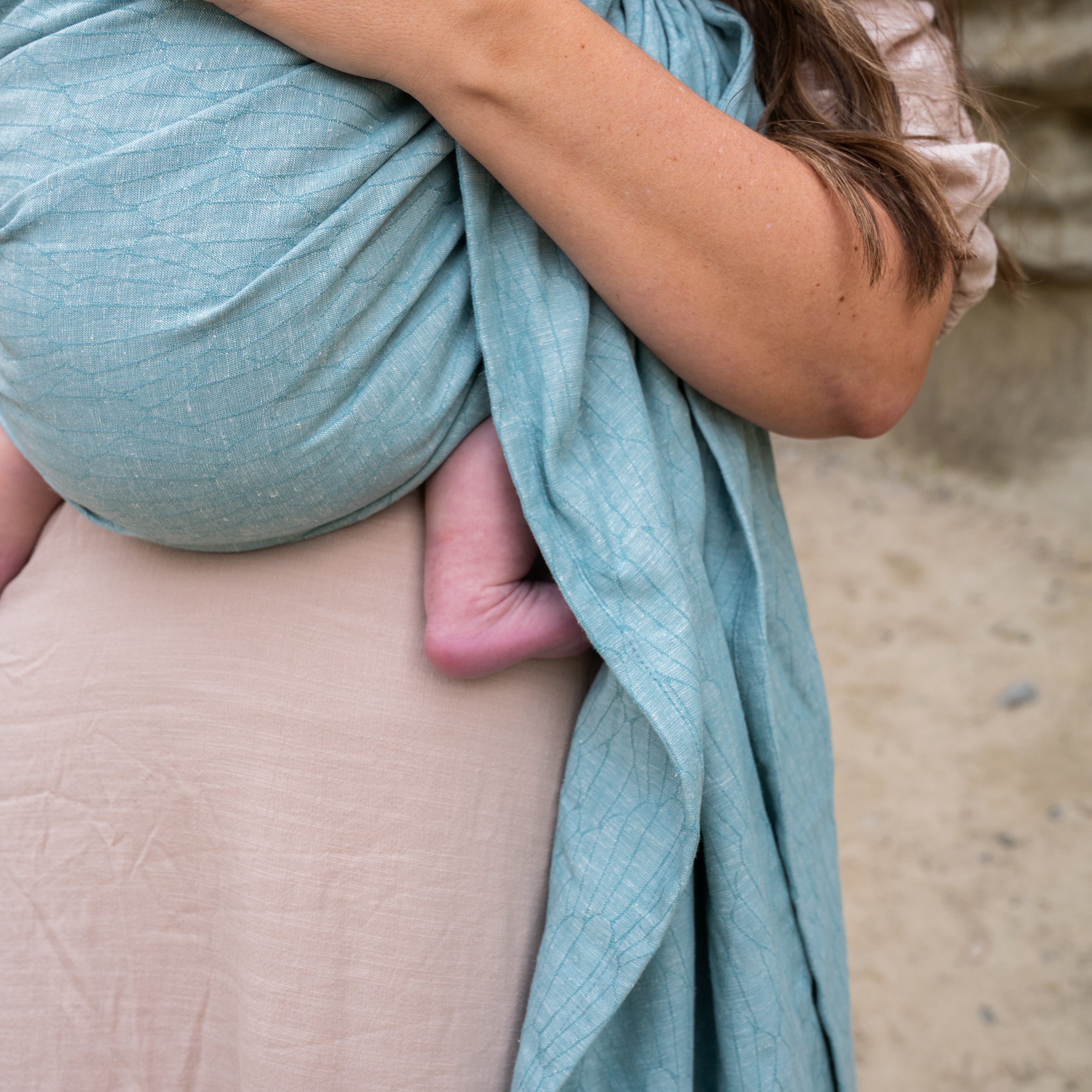 blue seashell woven patterned ring sling with champagne rings being worn by a brunette 