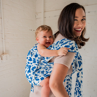 Mother back carrying her baby in a blue print meh dai baby carrier. 
