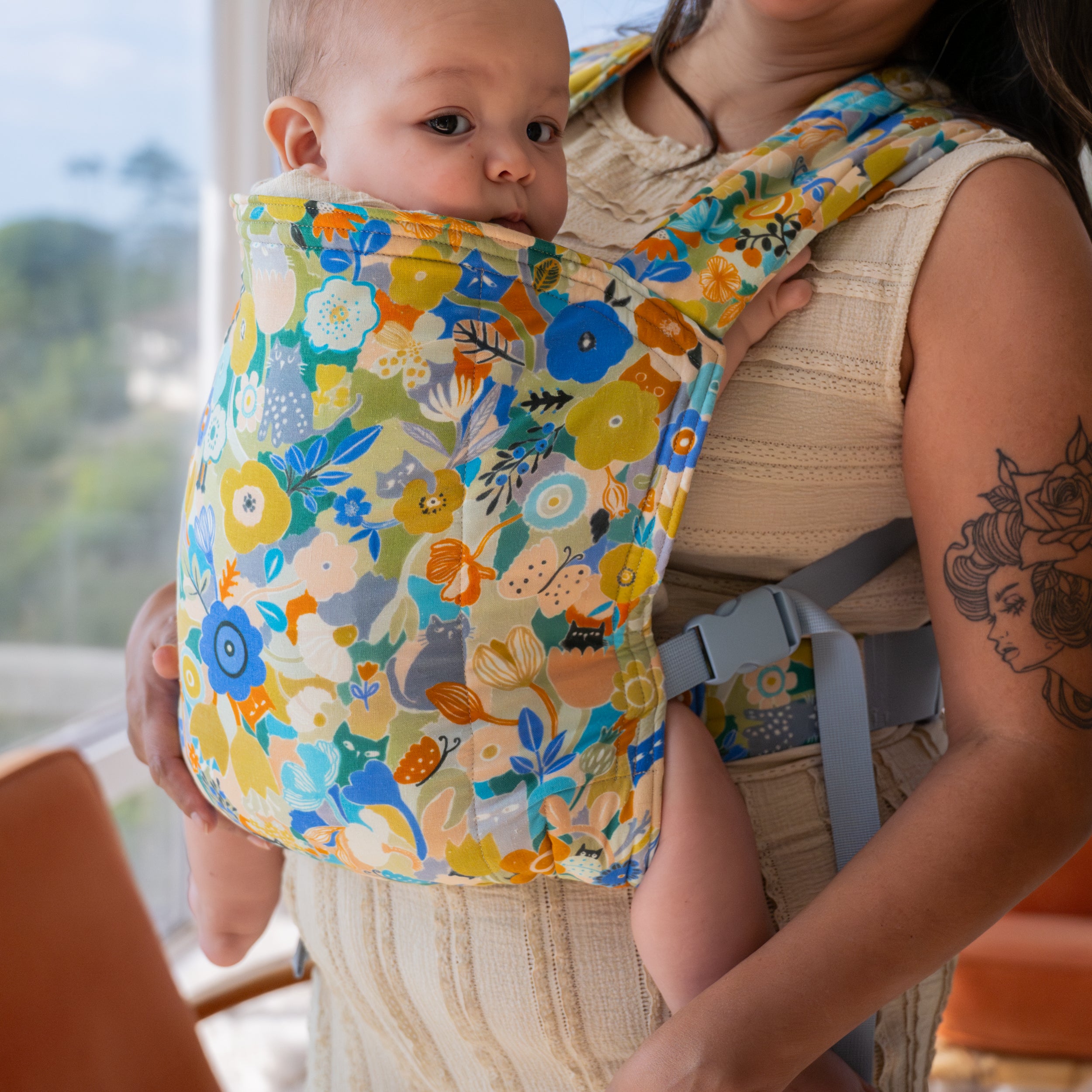 Baby in a floral baby buckle carrier with a woman holding