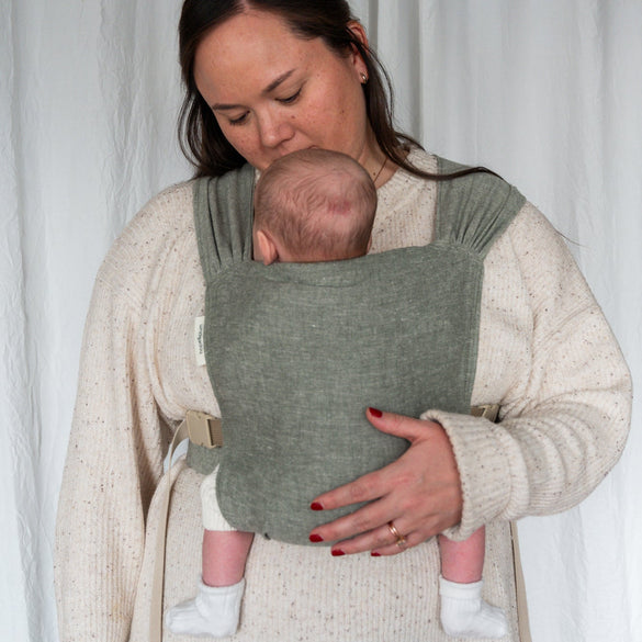 Woman in light green newborn carrier. 
