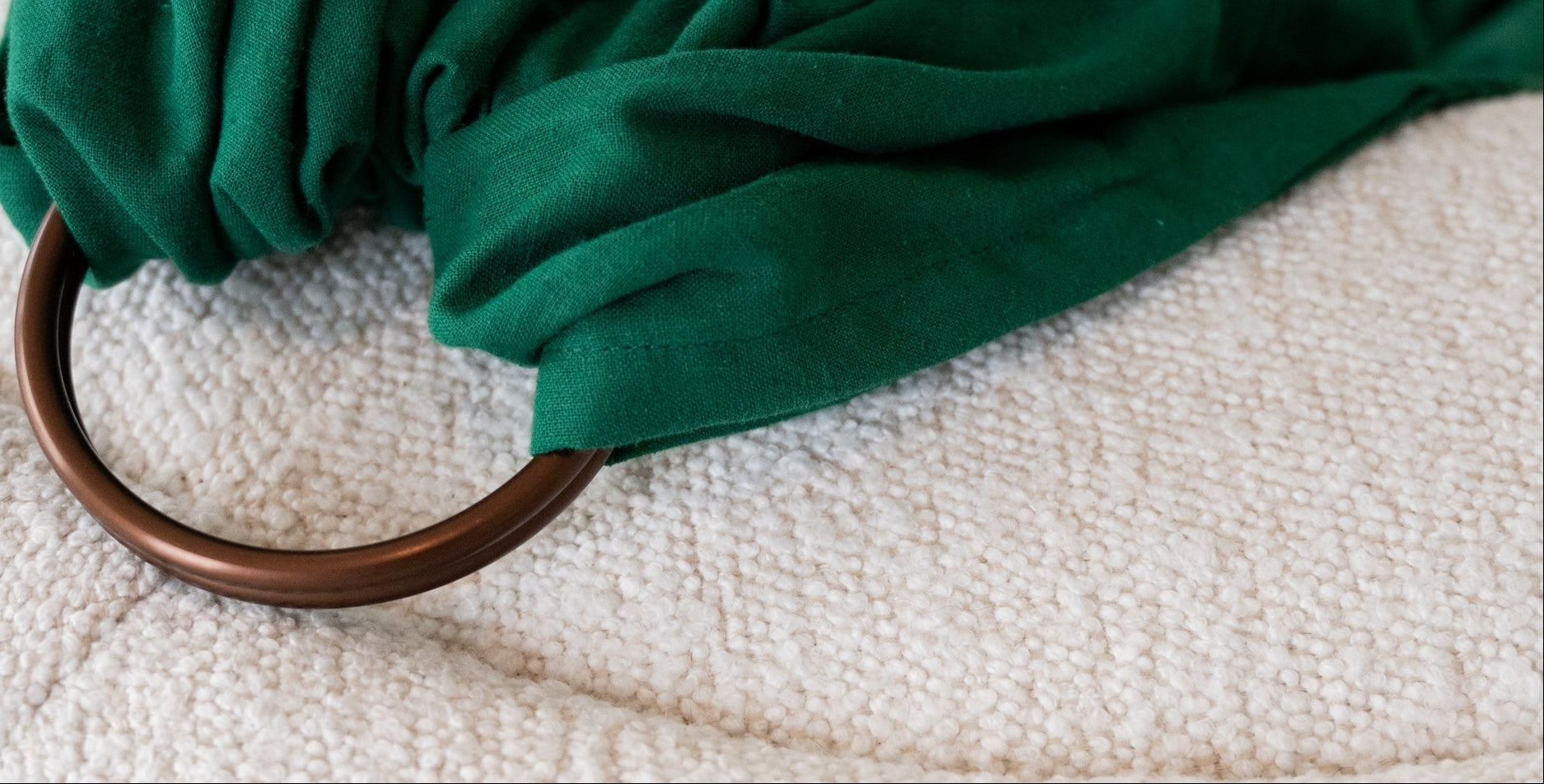 green ring sling with bronze rings laying flat on a white background