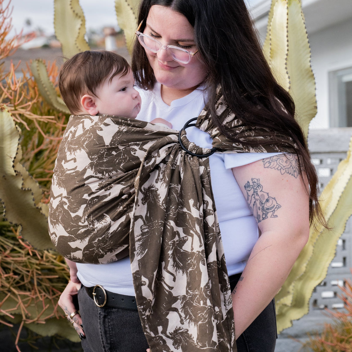 Ring Sling in Rodeo — caregiver holding a baby snuggled in the mustang print sling fabric.