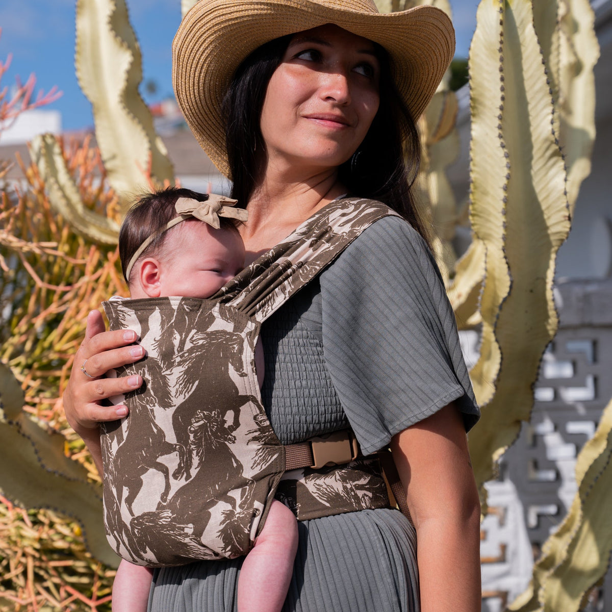 Sprout Newborn Carrier in Rodeo — close-up of a newborn nuzzled into the mustang print carrier panel.