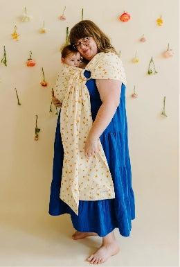 Plus-size mother wearing plus-size ring sling in floral print with infant.
