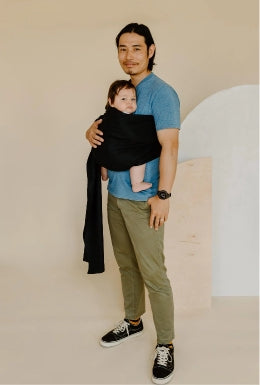 Father wearing baby in black ring sling baby carrier