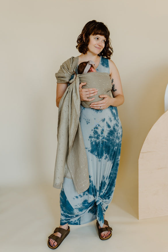 Mother carrying newborn in a taupe moon pattern woven ring sling.
