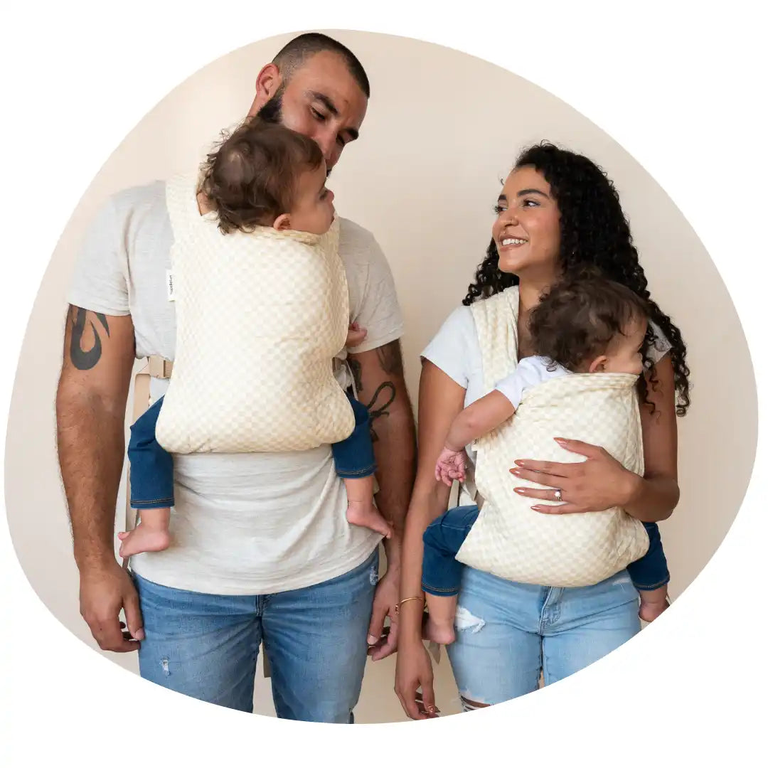 Parents wearing babies in quilted carriers.