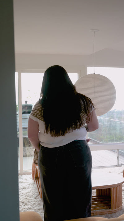 Ring Sling in Clove — side profile of a caregiver holding a baby in the gingham sling, near a glass door.