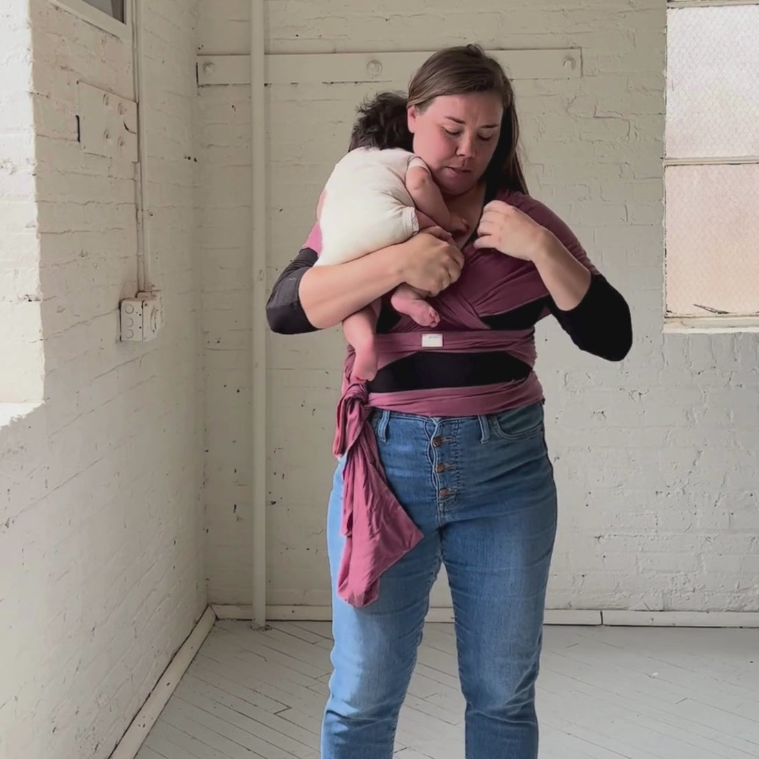 A video of Skye, hope&plum cofounder, wearing a rosewood stretchy baby wrap as she sways from side to side and puts her baby into it.